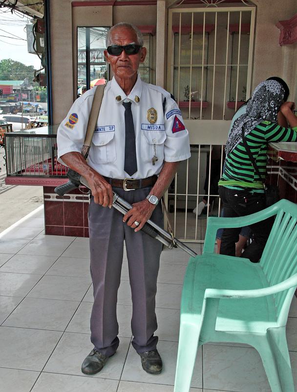 Philippines-78-Seib-2012.jpg - Watchman with pump gun in front of an exchange shop, Kidapawan (Photo by Roland Seib)